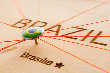 Brazil flag on the pushpin and red threads on the wooden map. Travel or logistic routes. Influence...