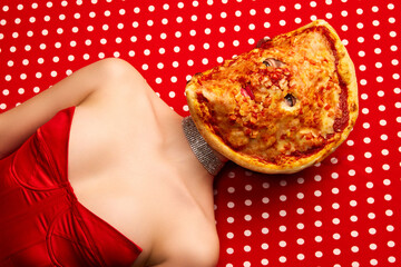 Weird people concept. Young girl lying on table with pizza on her face over red-white background....
