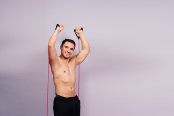 Athletic man skipping with a jump rope on grey background. Best cardio workout
