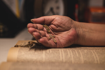 Concept of hope, faith and humility. Orthodox cross in the hand of an old woman on Holy Bible