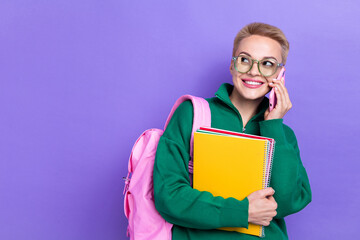 Portrait of positive lady hold book materials speak communicate telephone look empty space isolated on purple color background