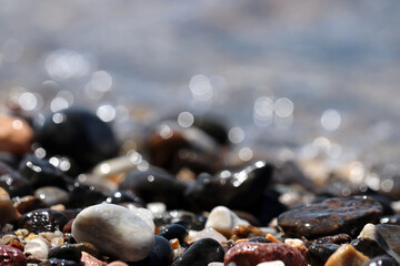 Wet pebble stones on blurred background of sea waves. Beach vacation concept