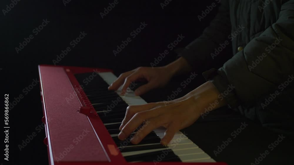Poster static close-up of a person playing a piano keyboard with both hands in a dimly lit room