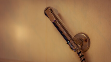 Old rusty hand held bidet in toilet need to maintenance.