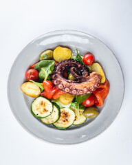 Mediterranean mixed salad with vegetables and grilled octopus. Top view of plate with salad. Octopus and vegetables dish.