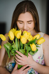 Surprise at 8 march, International Women's Day. Girl smiling and holding a bouquet of yellow tulips. Surprised woman. Holiday greeting card for Valentine's, and Mother's Day. Spring flowers. Closeup.