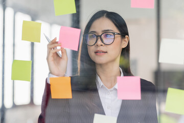 Business female employee with many conflicting priorities arranging sticky notes commenting and...