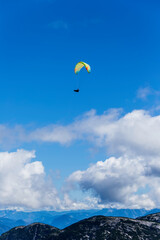 Fototapeta na wymiar Paraglider flying over mountain peaks on a sunny day