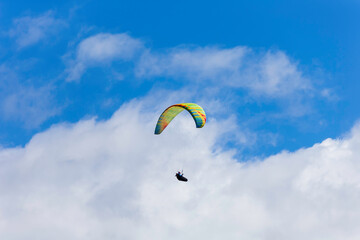 Paraglider flying against a blue sky on a sunny day