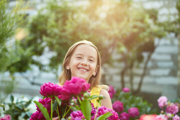 Happy little girl with braces in the garden in bushes of peonies