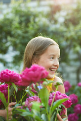 Happy little girl with braces in the garden in bushes of peonies
