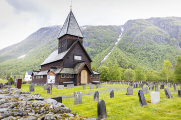 Typical antique wooden stave church with cemetery in Norway