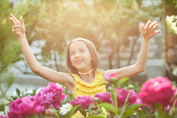 Fototapeta na wymiar Happy little girl with braces in the garden in bushes of peonies