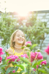 Fototapeta premium Happy little girl with braces in the garden in bushes of peonies