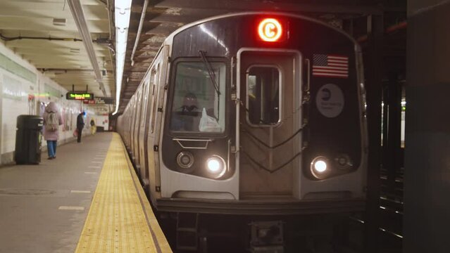 Train Arrives in NYC Subway Station, doors open, woman boards the train.  People practicing Social Distancing due to Covid-19 Pandemic Lockdown.  Brooklyn, New York City. 60 FPS.