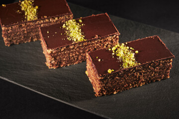 Chocolate cake with walnuts and pistachio isolated on black background. Pastry from homemade bakery