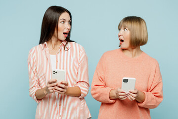 Amazed elder parent mom with young adult daughter two women together in casual clothes hold in hand...