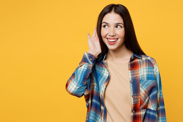 Fototapeta premium Young curious nosy smiling fun caucasian woman wear blue shirt beige t-shirt try to hear you overhear listening intently isolated on plain yellow background studio portrait. People lifestyle concept.