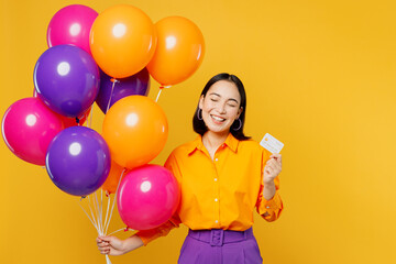 Fototapeta na wymiar Happy fun satisfied smiling young woman wearing casual clothes celebrating holding balloons using mobile cell phone close eyes isolated on plain yellow background. Birthday 8 14 holiday party concept.