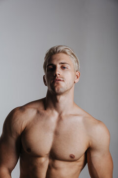 Blond male model portrait. Close up of handsome young man. Shirtless muscled guy in studio.