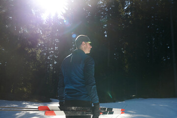 Portrait handsome male athlete with cross country skis in hands and goggles, training in snowy...