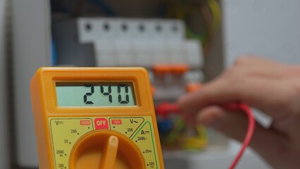 Yellow multimeter for measuring voltage close up. Work under voltage, electrician is checking...