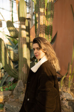 Smiling young white woman standing by cactus background.