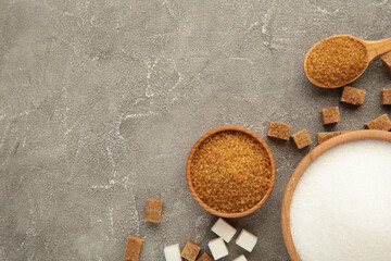 White and brown sugar in bowl on grey background.