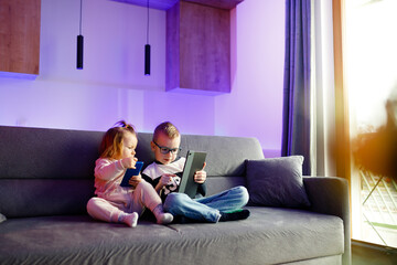 Danya and his sister Emilia play with mobile phones and tablets.