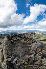 Fototapeta premium Remains of an old small mountain shelter made of stones to protect from inclement weather.