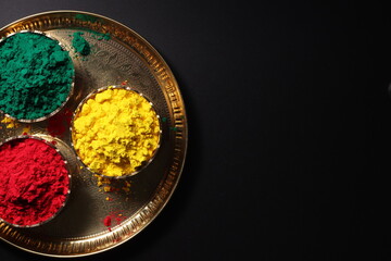 Holi Indian festival of colors, bright vibrant colors colours colorful Gulal Abeer in brass bowl isolated on black background