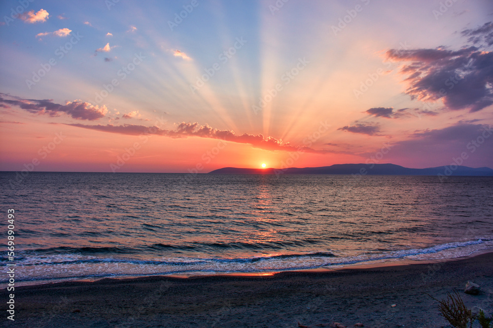 Wall mural Beautiful Aegean sunset over Seferihisar Izmir with an orange evening sky and light reflected in a calm seashore waves	