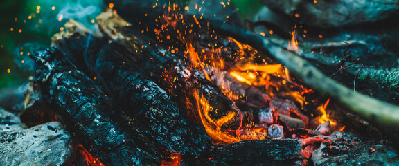 Vivid smoldered firewoods burned in fire close-up. Atmospheric background with orange flame of...