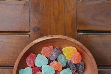 gummy candies of various colors and fruit flavors served in a wooden bowl.