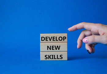 Develop New skills symbol. Concept word Develop New skills on wooden blocks. Businessman hand. Beautiful blue background. Business and Develop New skills concept. Copy space