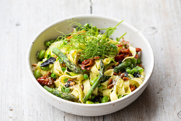 Tagliatelle pasta with asparagus, green peas and broad beans
