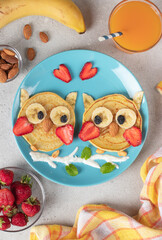 Owl-shaped pancakes with strawberries, bananas and almonds, a creative breakfast for kids or Valentine's Day