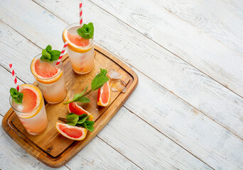 Three glasses of drink with slices of fresh grapefruit on wooden background. Creative minimal summer concept.