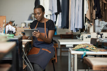 African female leather worker using a digital tablet at work