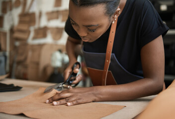 Young African female artisan cutting leather at a workbench