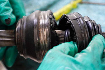 mechanic adding grease to cv joint rubber sleeves in garage,car wheel shaft mechanic has checked and repaired.