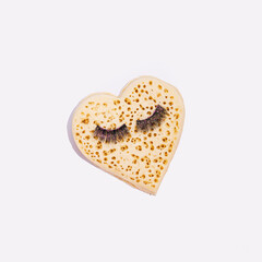 English crumpet, heart shape with fake eyelashes, creative love inspired layout, white background. 