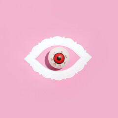 Eyeball model, oval paper frame, creative arrangement, pastel pink background. 