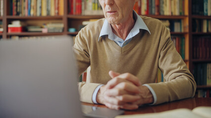 Senior university professor teaching lecture on laptop, sitting at the library