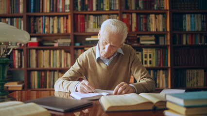 Male scientist doing research in the library, reading books and writing down notes