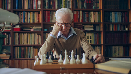 Serious grandmaster thinking over chess composition, sitting at the library, hobby