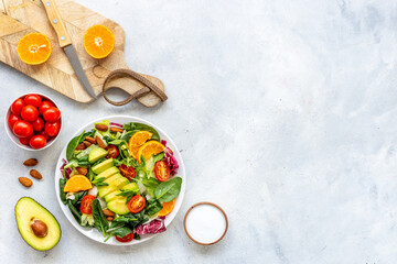 Overhead view of cooking healthy green salad with avocado and tomatoes