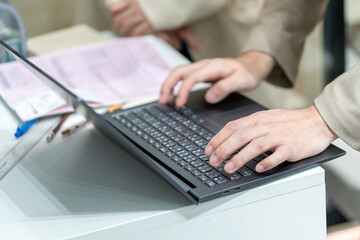 Employee’s hand  using office computer Typing an email on a computer keyboard and doing online research working in an office.