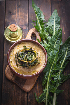 Pugliese recipe   Fave e cicoria:  fava beans or broad beans porridge  with Asparagus chicory, italian dandelion chicory or Catalonian chicory on the wooden  rustic table, tradition poor Bari cuisine 