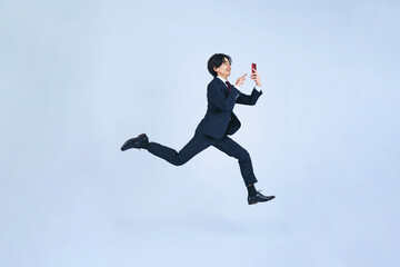 Fototapeta na wymiar スマホを使いながらジャンプする男性